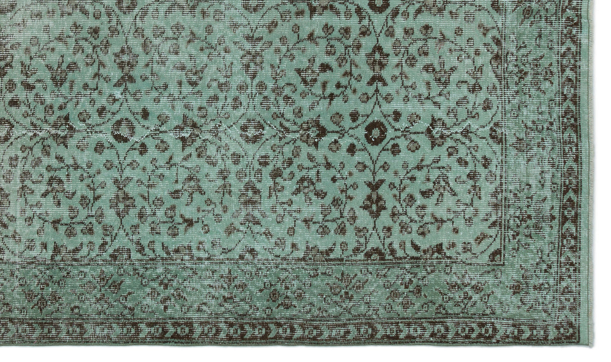 Distressed mint green rug with a dark brown floral vine pattern and a decorative border.