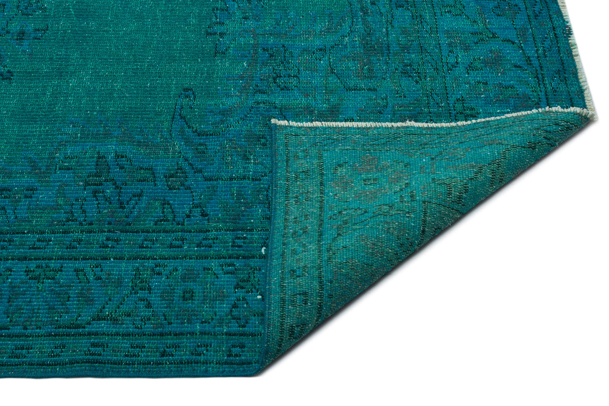 Teal distressed traditional rug with a folded corner revealing the underside and fringe detail.