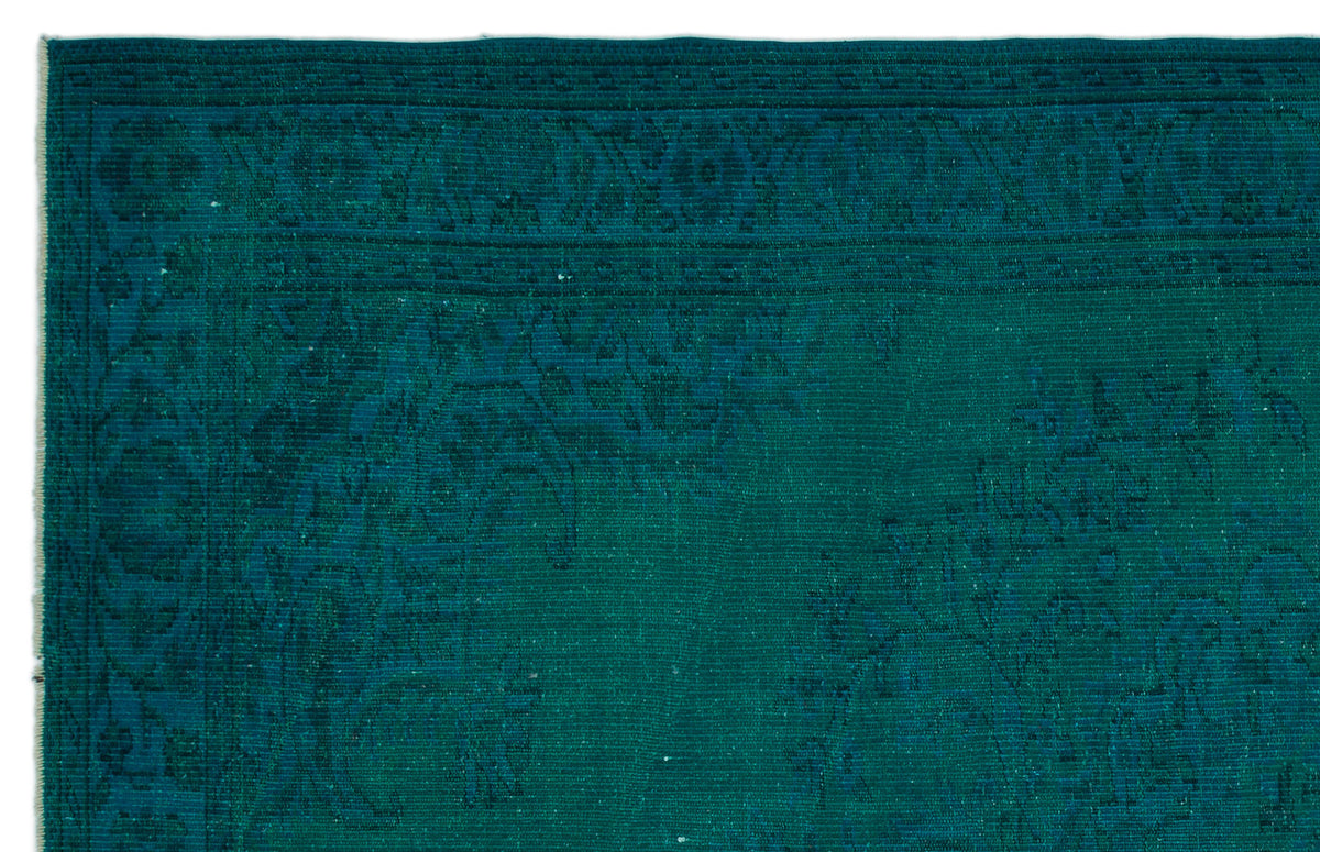 Teal monochromatic rug with a traditional ornate border and subtle floral medallion pattern.