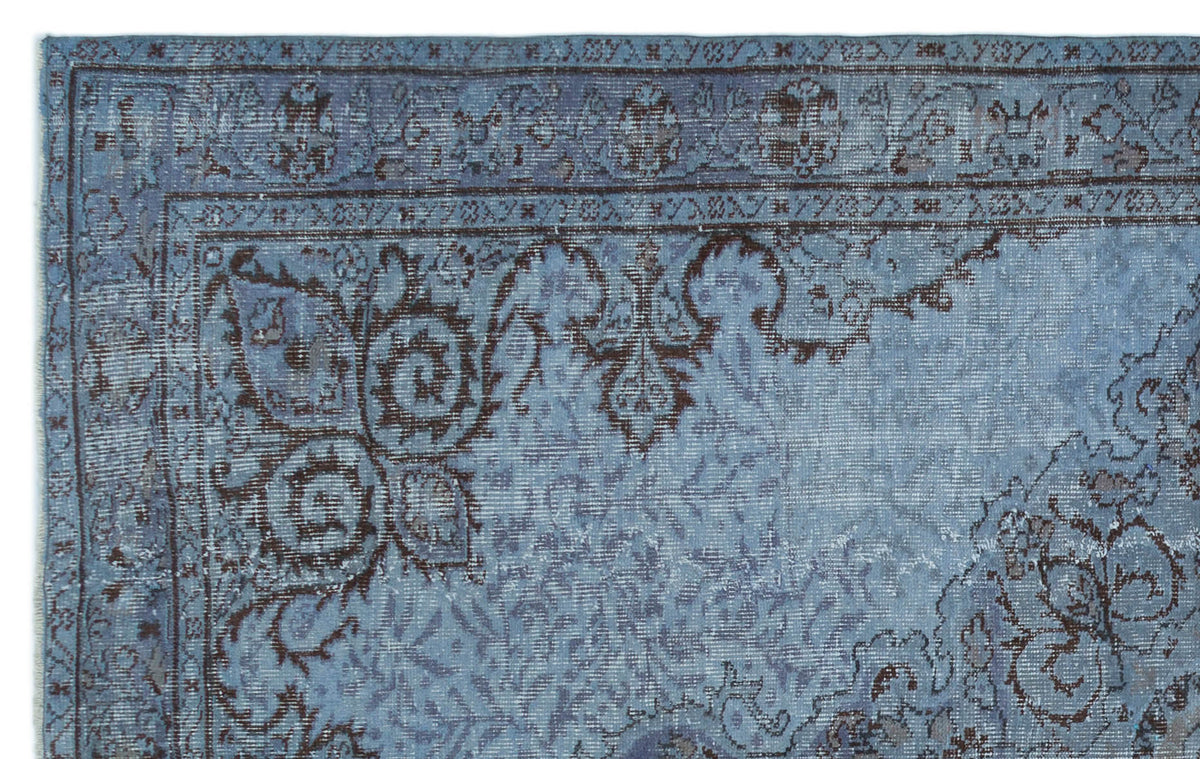 Blue and dark brown traditional rug with a distressed floral medallion pattern on a white background.