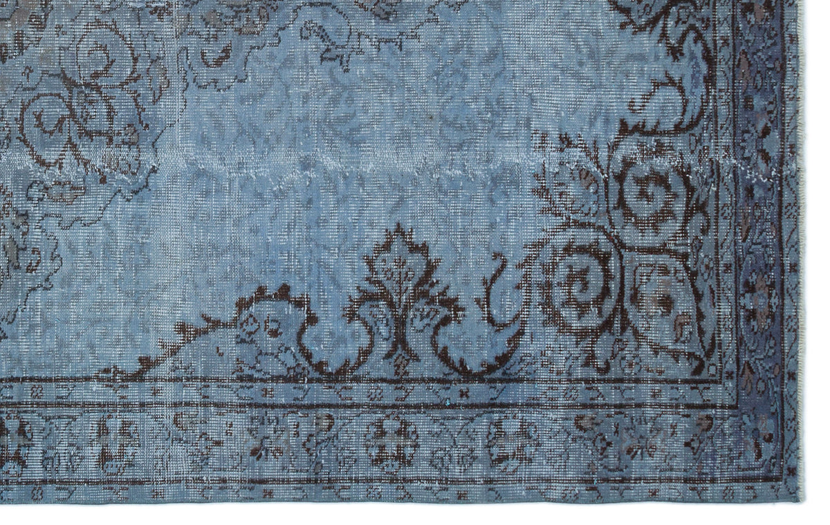 Distressed blue rug with a dark brown traditional floral medallion pattern and a detailed border.