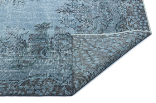 Load image 1 in gallery view. Blue and grey distressed floral rug with a corner folded over to reveal the woven backing.