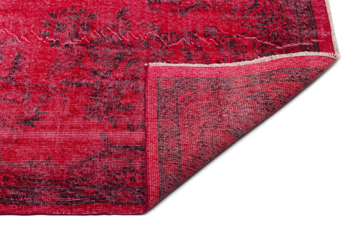 Load image 1 in gallery view. Vibrant red rug with a distressed black floral pattern and a folded corner showing the woven backing.