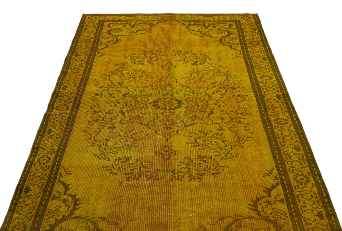 Mustard yellow distressed rug with a dark brown central floral medallion and ornate border on a white background.