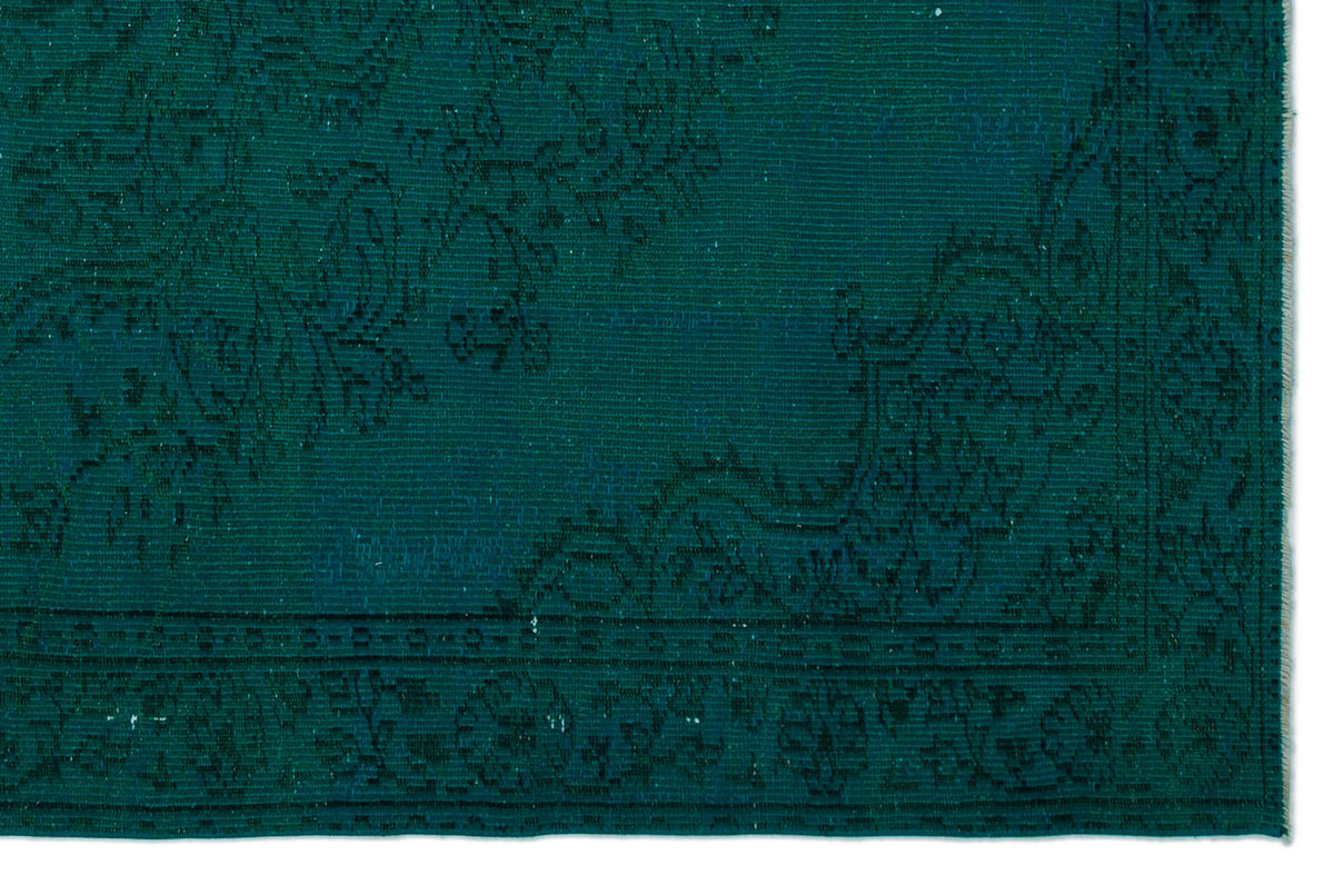 Deep teal rug with a subtle, tonal floral medallion pattern and a decorative border.