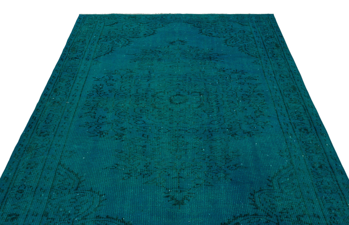 Teal vintage-style rug with a faded black traditional medallion pattern on a white background.