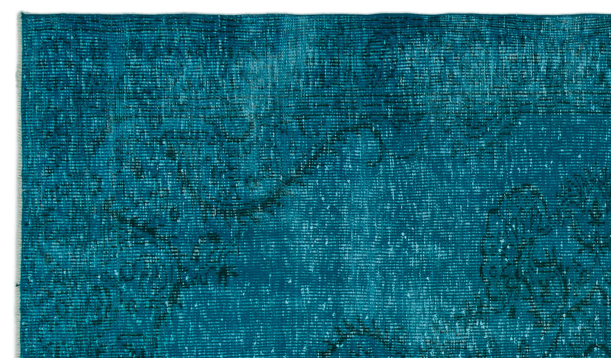 Teal distressed rug with a faint, dark traditional floral pattern and visible woven texture.