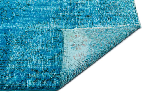 Load image 1 in gallery view. Bright blue distressed rug with a faded traditional pattern, shown with a corner folded over to reveal the backing.