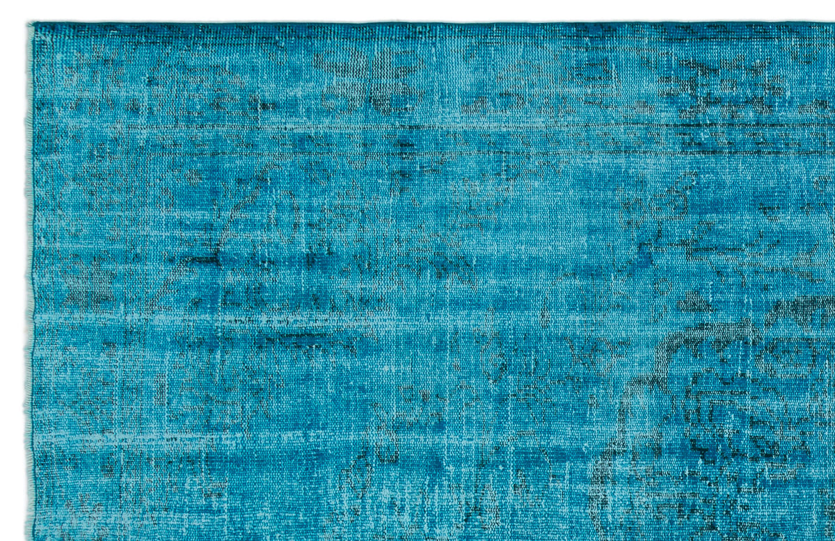Bright turquoise rug with a distressed, faded traditional pattern and dark charcoal accents.