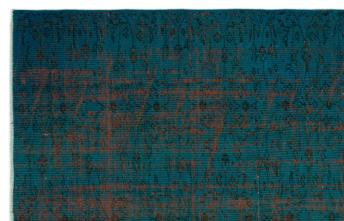 Teal rug with a distressed, dark brown traditional floral pattern and visible woven texture.