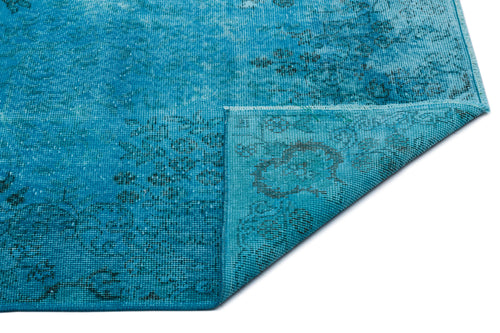 Load image 1 in gallery view. Bright turquoise distressed rug with a faded dark floral pattern and a folded corner showing the woven backing.