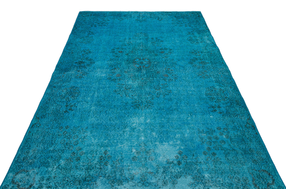 Bright turquoise distressed rug with a faint, dark floral medallion pattern.
