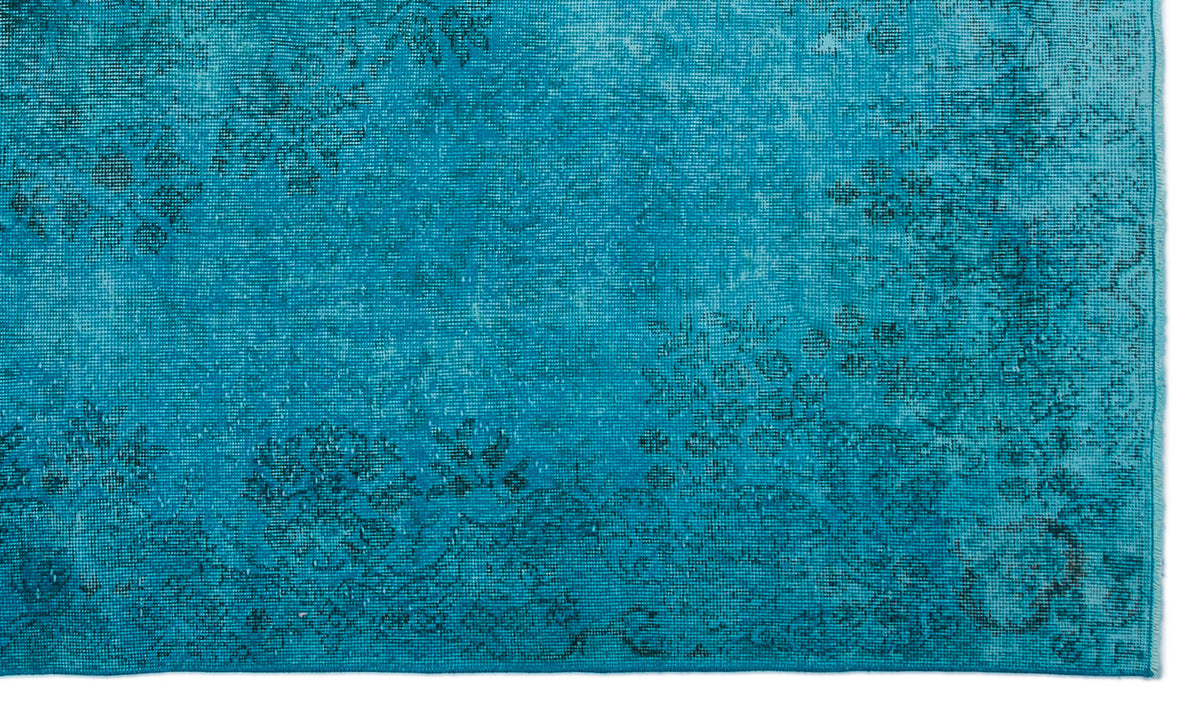 Bright turquoise rug with a distressed, faded floral medallion pattern.