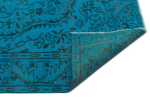Load image 1 in gallery view. Bright turquoise rug with a dark charcoal floral pattern and a folded corner revealing the underside.