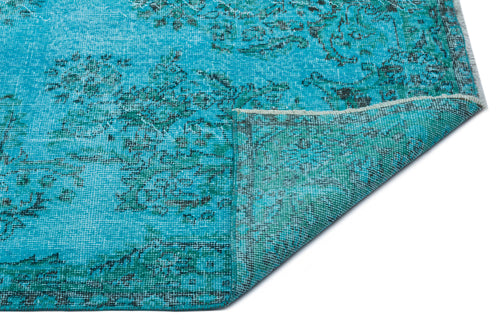 Load image 1 in gallery view. Bright turquoise rug with a distressed floral medallion pattern and a folded corner, isolated on a white background.