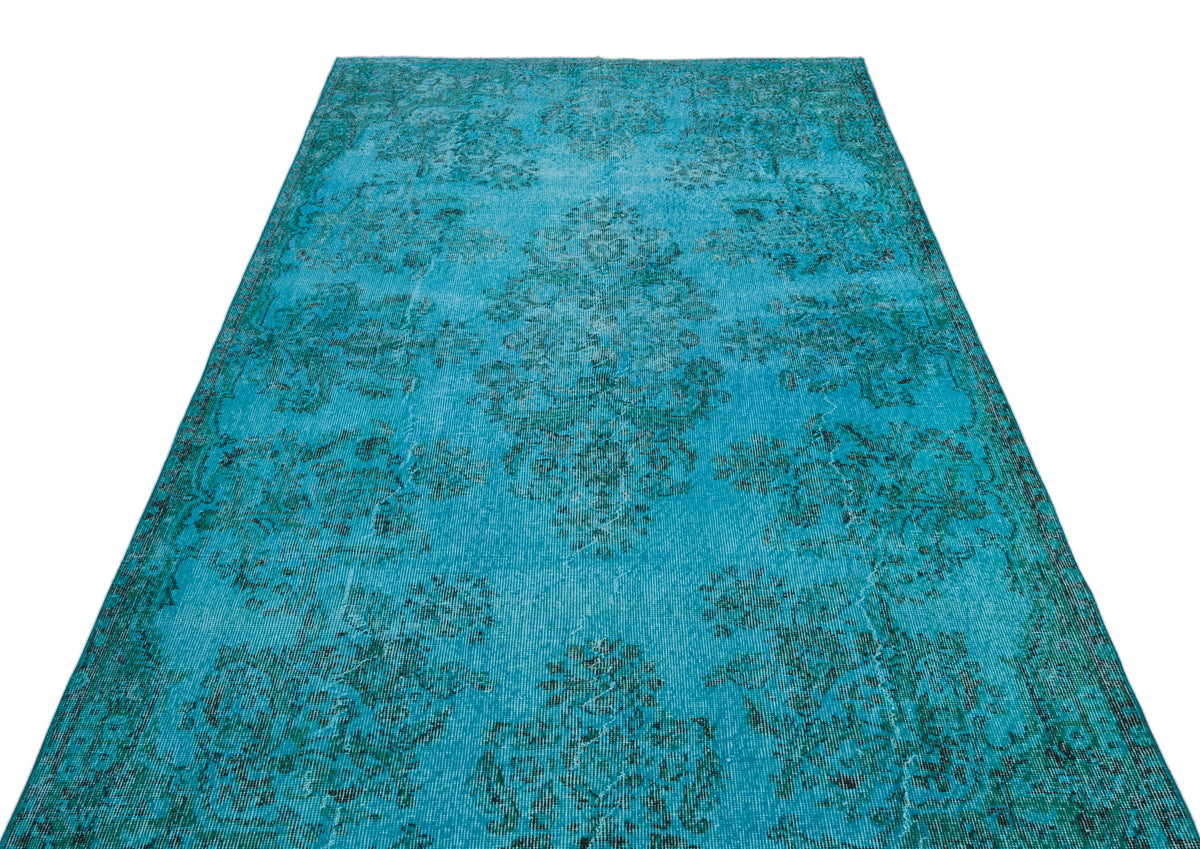 Bright turquoise distressed rug with a dark teal traditional floral medallion pattern on a white background.