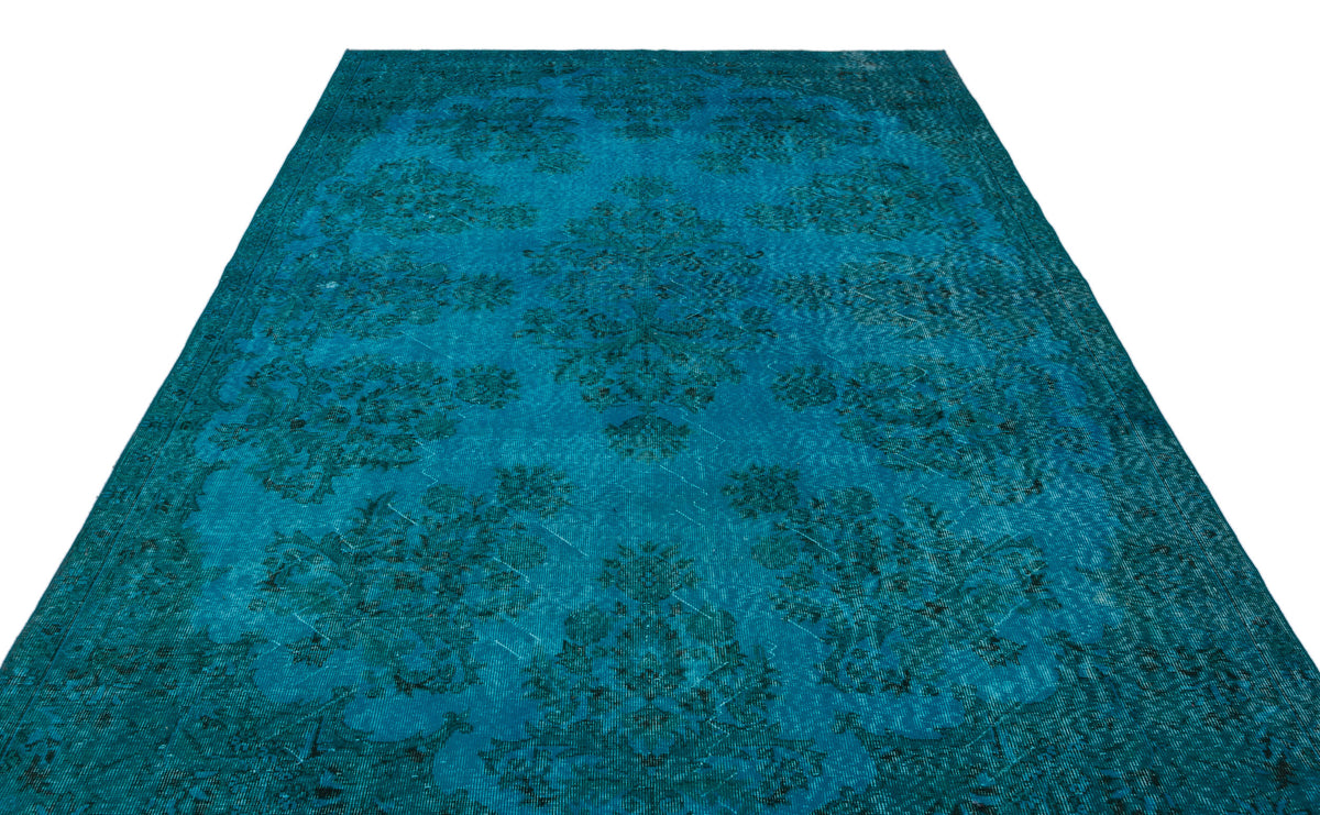Teal distressed area rug with a dark floral medallion pattern on a white background.