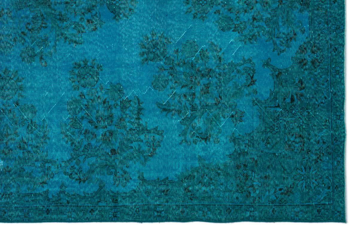 Teal rug with a distressed, monochromatic floral medallion pattern and a detailed border.