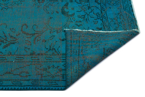 Load image 1 in gallery view. Teal and dark grey distressed rug with a traditional floral pattern, shown with a corner folded over on a white background.