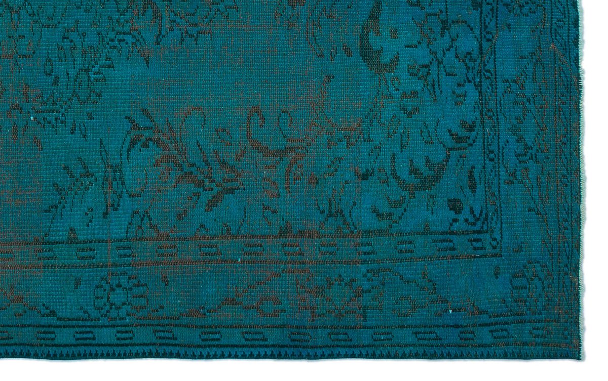 Teal rug with a dark brown traditional floral medallion pattern and a geometric border.