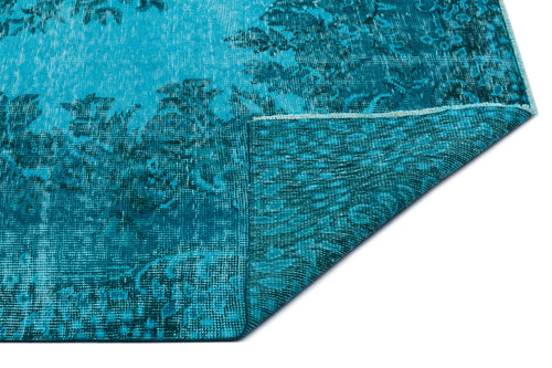 Load image 1 in gallery view. Teal and turquoise distressed rug with a faded floral pattern, shown with a corner folded over on a white background.