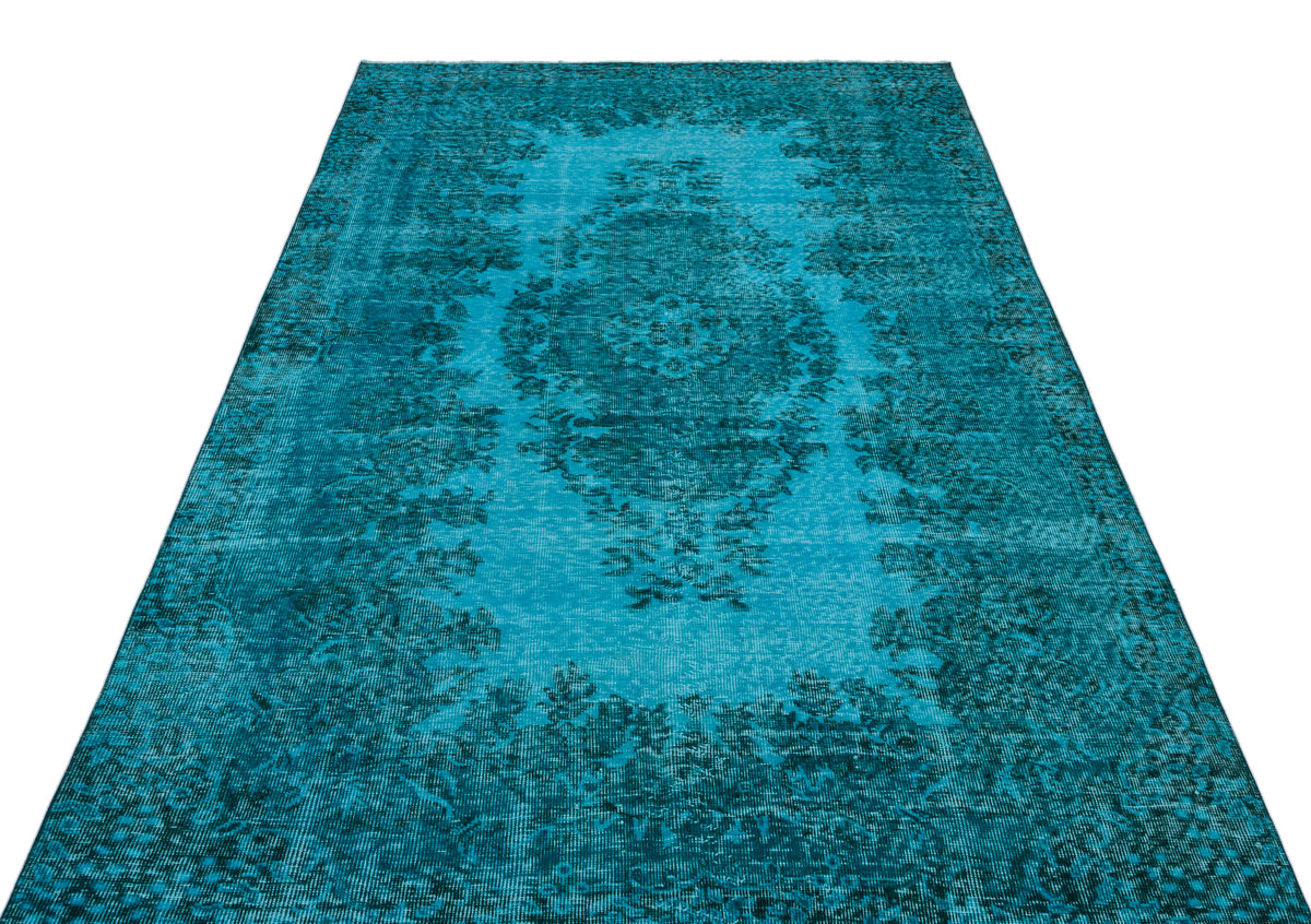Distressed turquoise rug with a dark blue central floral medallion and ornate border pattern on a white background.