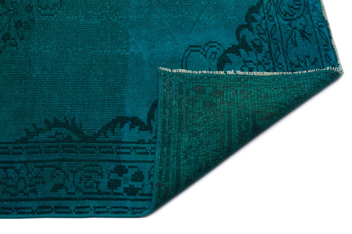 Teal and black traditional rug with a folded corner revealing the woven backing.