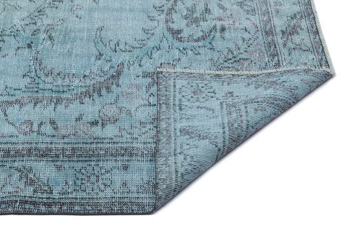Load image 1 in gallery view. Light blue distressed rug with a dark grey traditional floral pattern and a folded corner showing the woven backing.