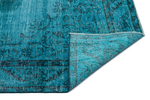 Load image 1 in gallery view. Teal distressed rug with a dark floral medallion pattern, shown with a corner folded over on a white background.