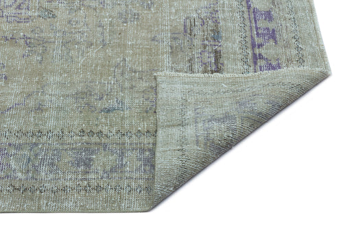 Load image 1 in gallery view. Beige and purple distressed vintage-style rug with a folded corner showing the woven backing.