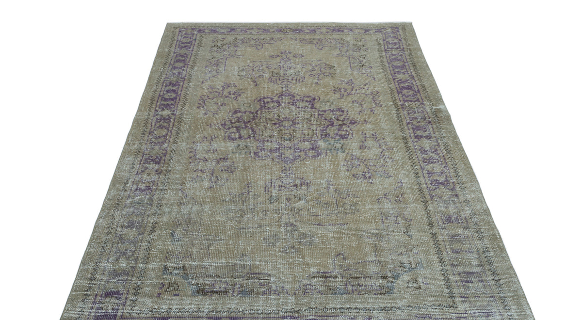 Distressed beige and purple vintage-style rug with a central medallion and ornate border pattern.