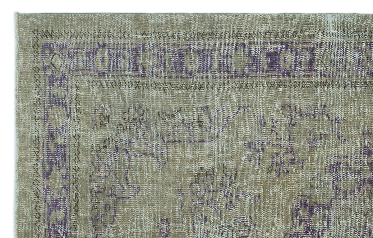 Distressed beige and purple rug with a faded traditional floral medallion pattern and a geometric border.