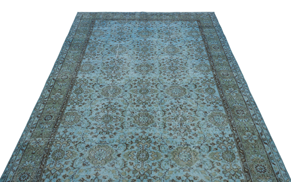 Light blue and sage green distressed rug with a traditional floral medallion pattern and a dark border.