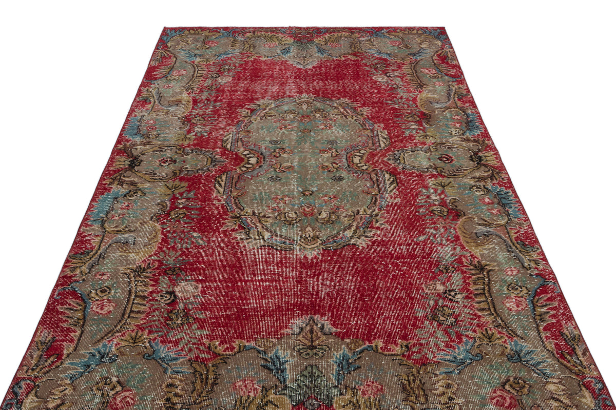 Distressed red Persian-style rug with a central sage green medallion and intricate floral border patterns.
