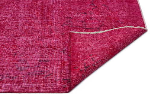 Load image 1 in gallery view. Magenta distressed rug with a faded traditional pattern and a folded corner, isolated on a white background.