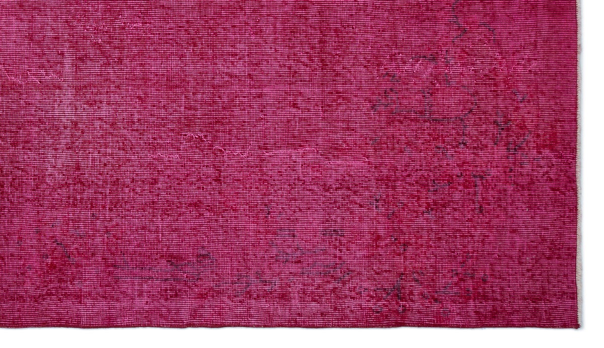 Magenta overdyed vintage rug with a distressed, faded texture and subtle dark charcoal pattern details.
