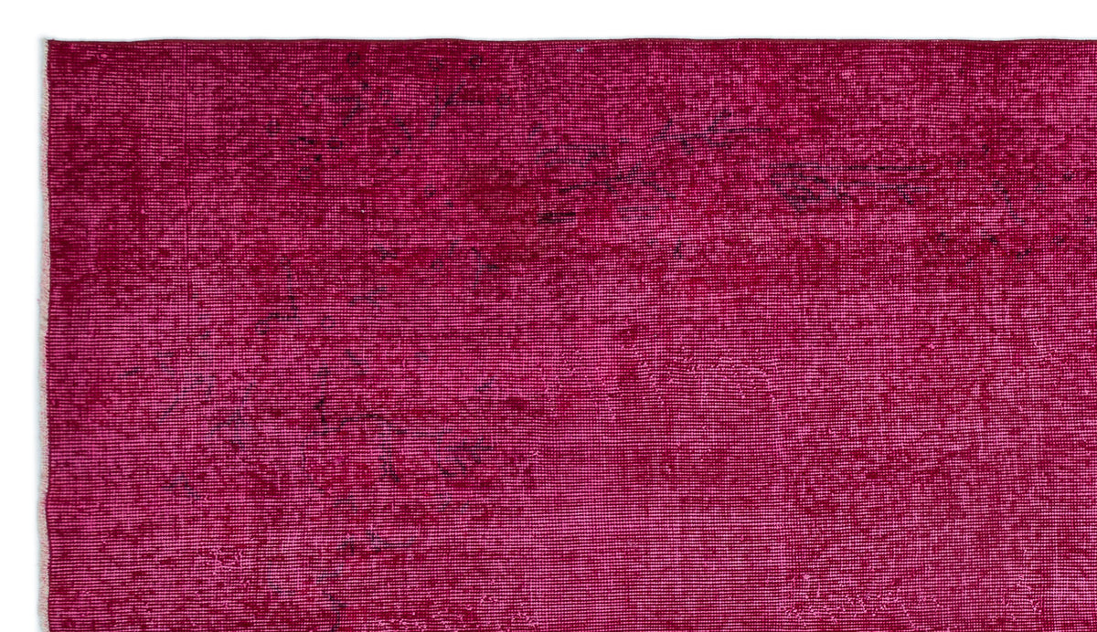 Magenta distressed rug with a faded, textured appearance and subtle dark charcoal accents.