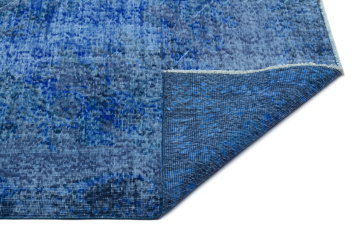 Blue distressed-pattern rug with a folded corner revealing the woven backing, isolated on a white background.