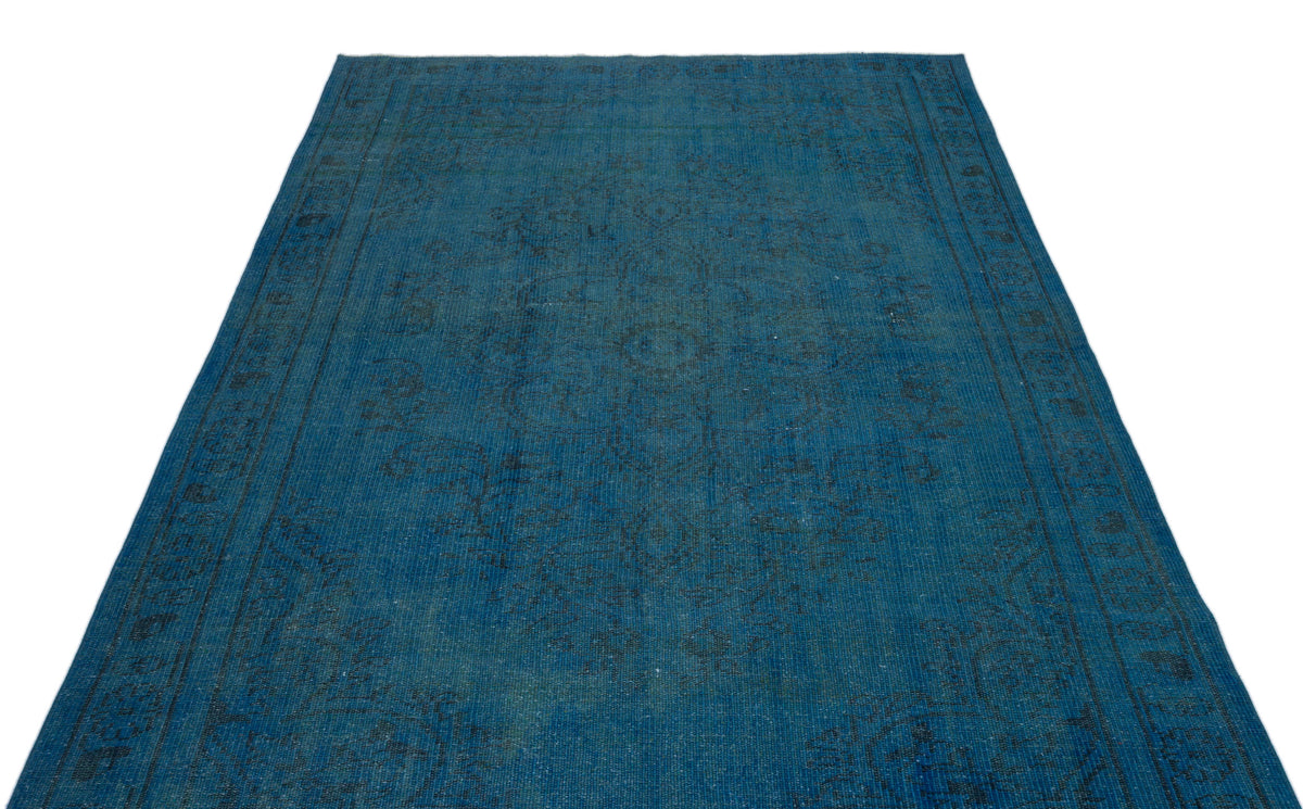 Deep blue vintage-style rug with a faded, intricate black floral medallion pattern and a decorative border.