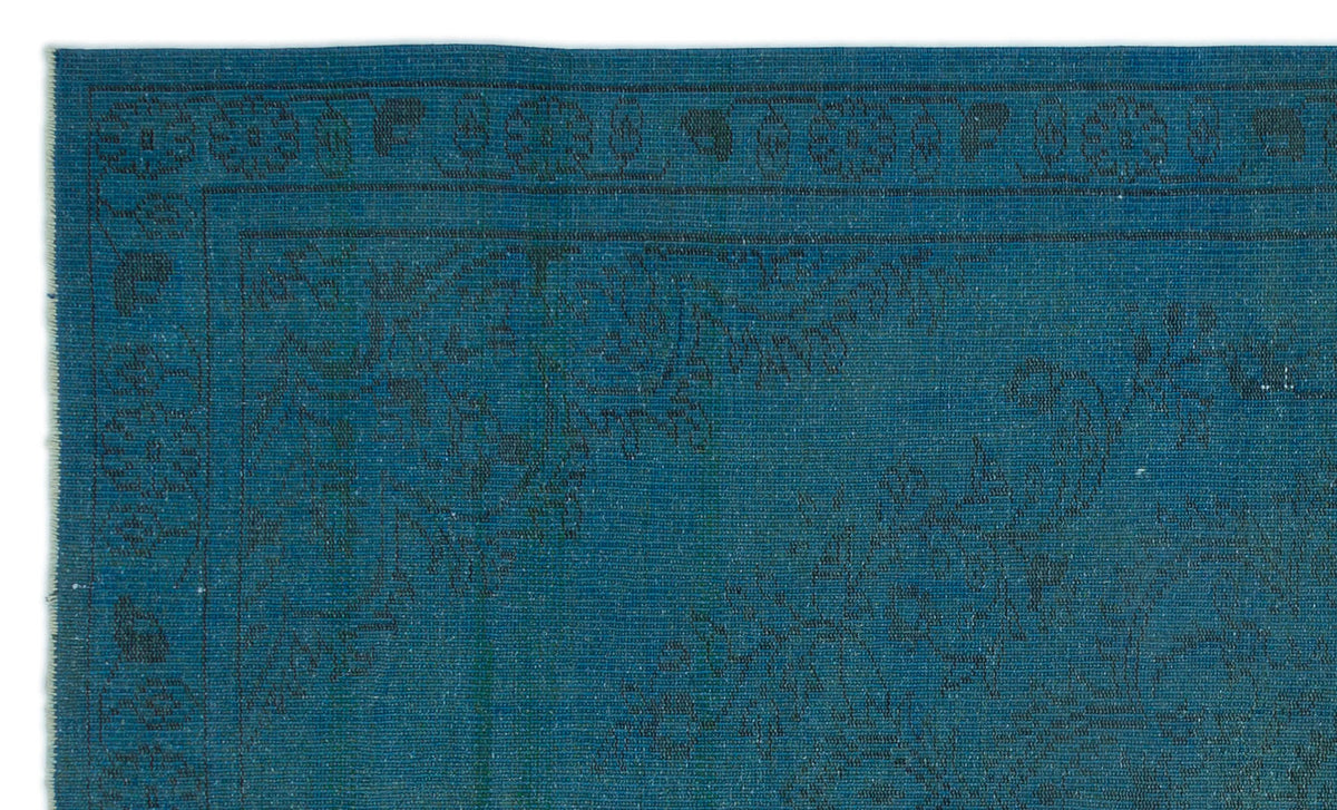 Teal rug with a dark, subtle floral border and intricate tonal pattern.