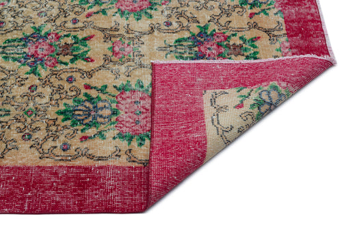 Load image 1 in gallery view. Beige rug with a floral pattern in pink, green, and blue, featuring a wide red border and a folded corner.