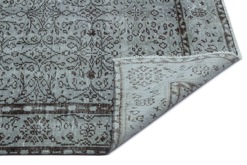 Load image 1 in gallery view. Grey and brown distressed rug with a traditional floral medallion pattern and a folded corner showing the backing.