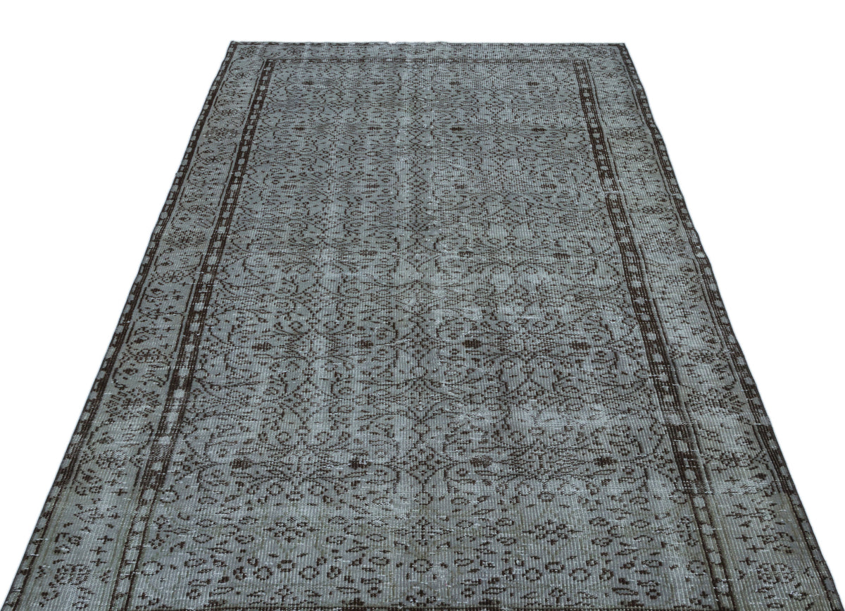 Grey and dark brown distressed rug with an intricate traditional floral pattern and a bordered edge.