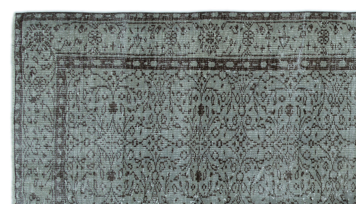 Distressed sage green and dark brown rug with a traditional floral medallion border and intricate vine pattern.