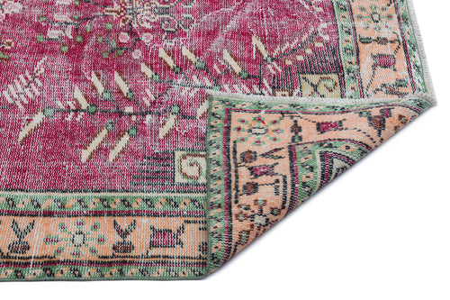 Load image 1 in gallery view. Distressed magenta, peach, and green rug with a traditional floral medallion pattern and a folded corner.