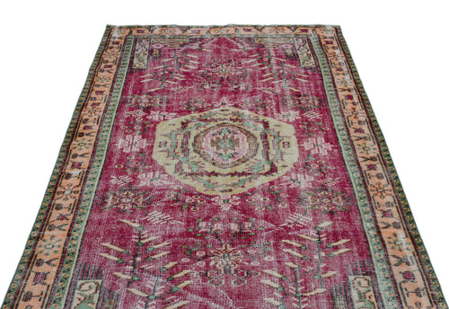 Load image 1 in gallery view. Distressed magenta vintage-style rug with a central beige medallion, geometric patterns, and a multi-colored border.