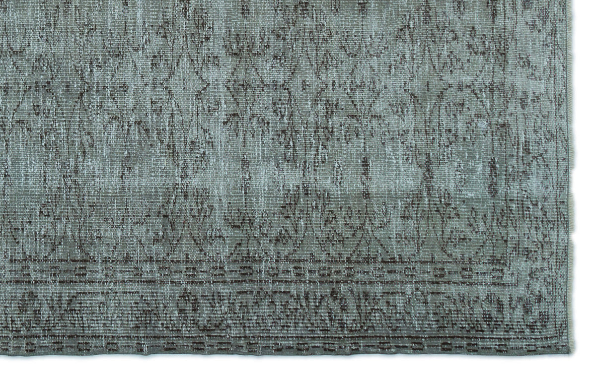 Sage green and brown distressed rug with a faded traditional floral pattern and a bordered edge.