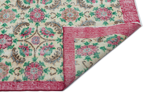Load image 1 in gallery view. Cream rug with a floral medallion pattern in red, green, and brown, featuring a folded corner on a white background.