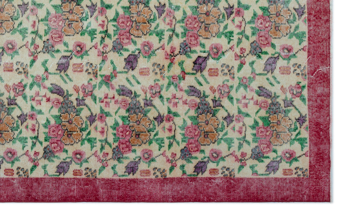 Cream rug with a multi-colored floral pattern in pink, orange, and purple, framed by a solid red border.