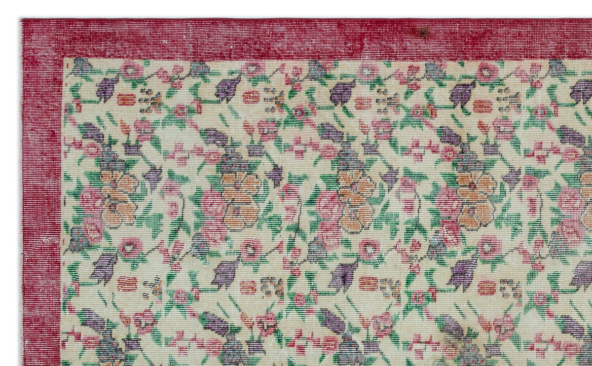 Cream rug with a red border and a repeating floral pattern in pink, purple, orange, and green.